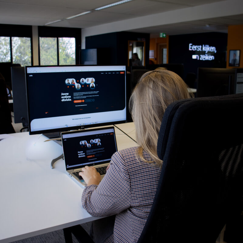 Witte vrouw met kop koffie lachend achter laptop