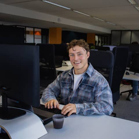 Witte man lachend achter computer