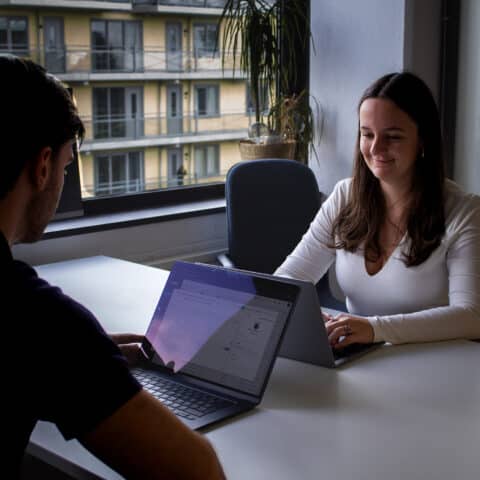 Twee witte mensen aan het overleggen met laptops