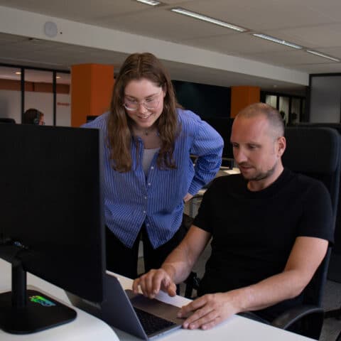 Collega’s die met elkaar praten en naar het computerscherm kijken.