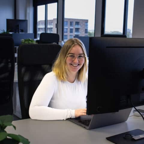 Witte vrouw lachend achter laptop aan het werk