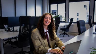 Getinte vrouw glimlachend aan het werken met laptop