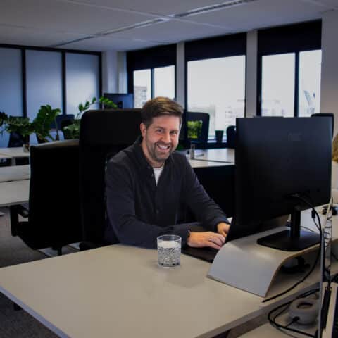 Witte man lachend achter computerscherm