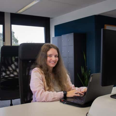 Witte vrouw aan lachend aan het werk achter laptop