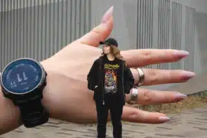 Witte vrouw dat voor een hand staat met horloge bij een gebouw